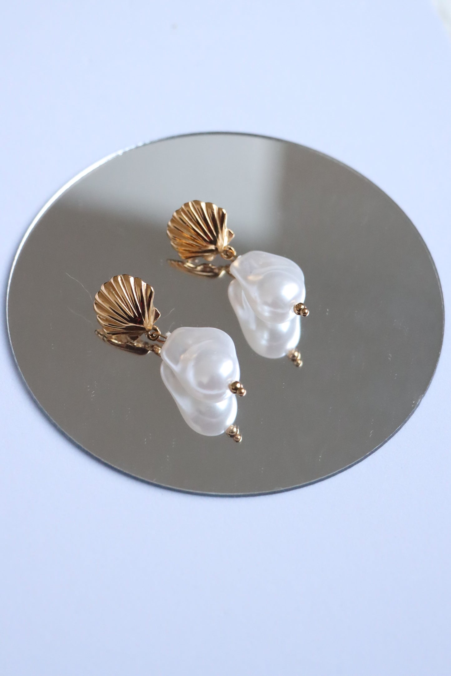 Brincos em formato de concha com pedra pendente