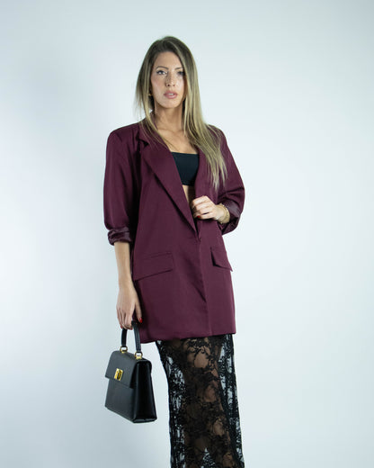 Mulher a usar blazer oversized bordeaux claro, peça feminina e versátil.


